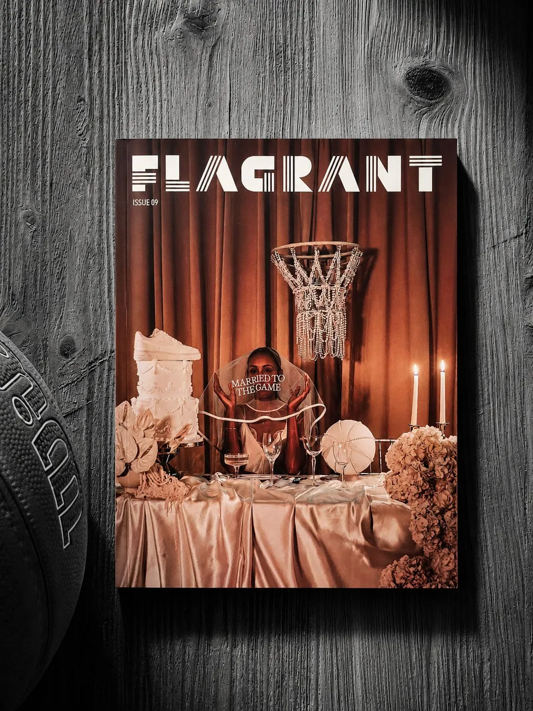 An issue of Flagrant magazine in warm orange tones on a monochrome wooden surface