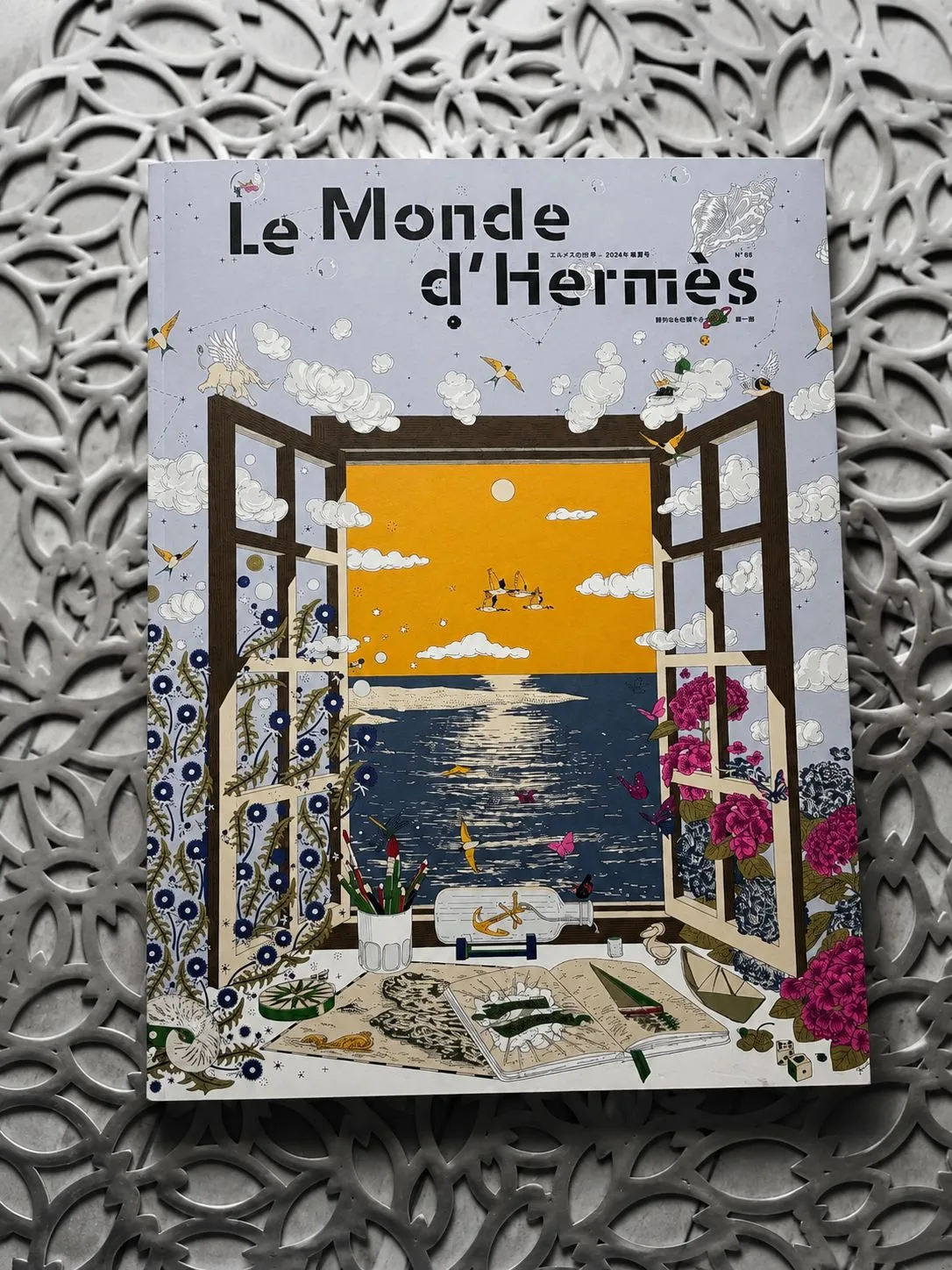 Le Monde d’Hermès magazine, its illustrated orange window in colour against a monochrome patterned surface